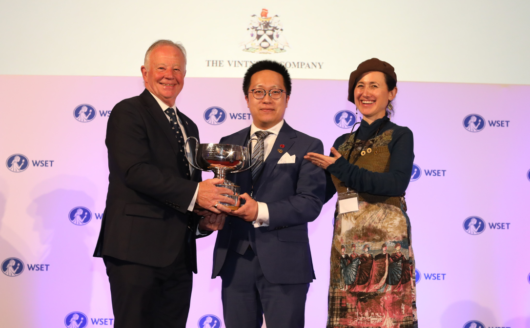The winner of the Vintners Cup holding a trophy on stage with Ian Harris MBE and Dr Laura Catena